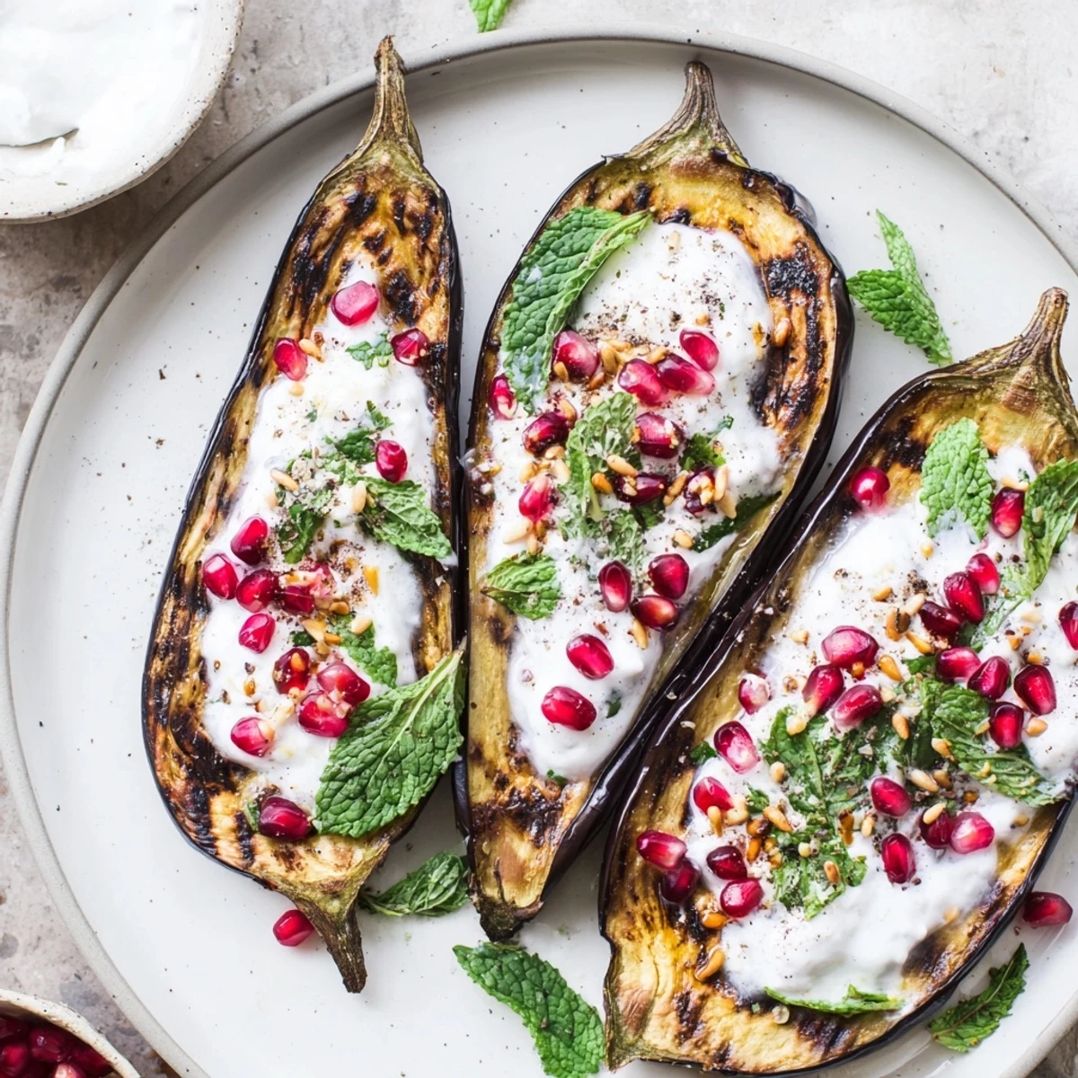 Golden, roasted eggplant halves are drizzled with creamy yogurt sauce and bursting pomegranate seeds.