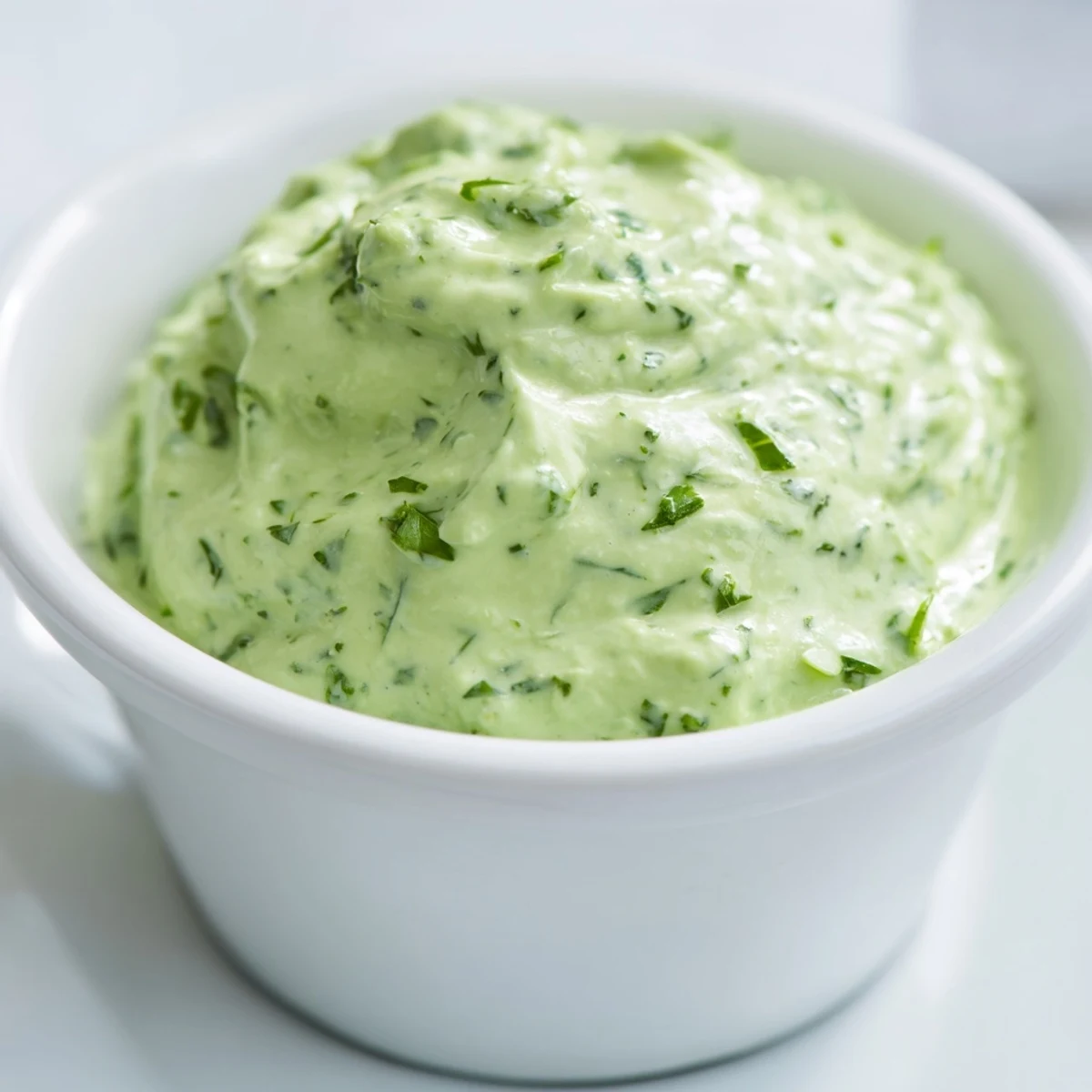 A close-up of homemade green goddess dressing drizzled over a crisp salad.