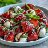 Vibrant strawberry Caprese salad glistening with balsamic glaze and fresh basil.