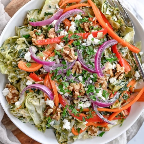 A vibrant bowl of Cooked and Loved Cabbage Salad with sautéed cabbage, crisp carrots, and fresh parsley tossed in a tangy dressing.