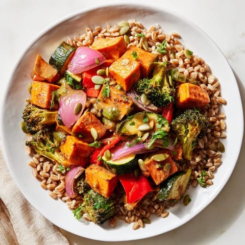 A close-up of a Hearty Roasted Vegetable and Farro Grain Bowl, drizzled with lemon-tahini dressing.
