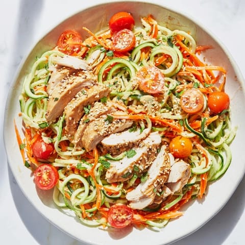 A beautiful bowl of Protein Cucumber Salad showing tender chicken atop fresh spiralized cucumbers.