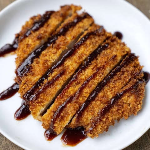 Freshly fried Chicken Katsu cutlet resting on shredded cabbage with a side of steamed rice.  