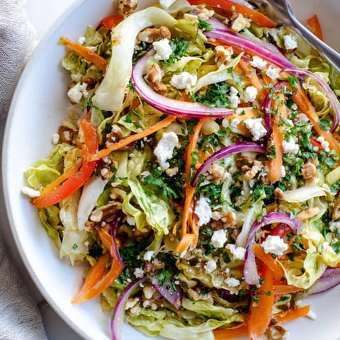 Warm Cooked and Loved Cabbage Salad served as a vibrant side dish, featuring tender vegetables topped with crunchy walnuts and crumbled feta.