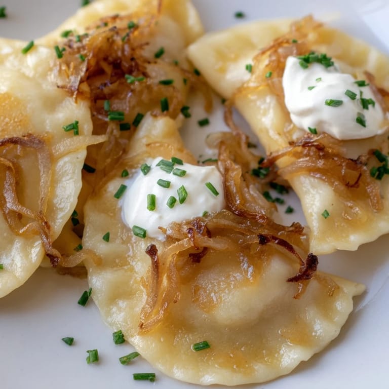 Freshly made Polish pierogi, steaming slightly, presented with caramelized onions and sour cream.