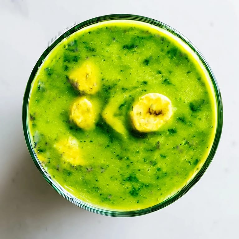 Fresh spinach blended with mango and pineapple in a vibrant green smoothie, ready to sip and enjoy.