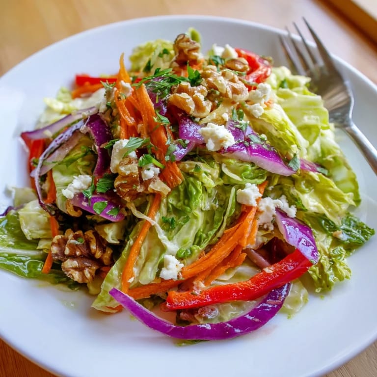 A close-up of Cooked and Loved Cabbage Salad showcasing glossy, herbaceous dressing coating the sautéed cabbage and colorful vegetable ribbons.