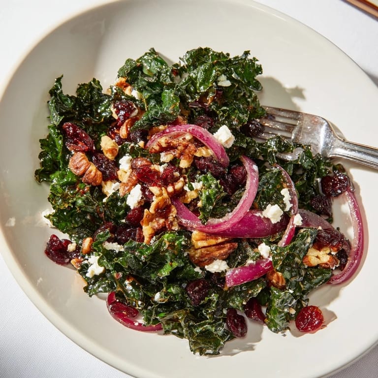 Freshly dressed kale salad with maple mustard glaze, featuring sliced red onion and crumbled feta for extra flavor.  