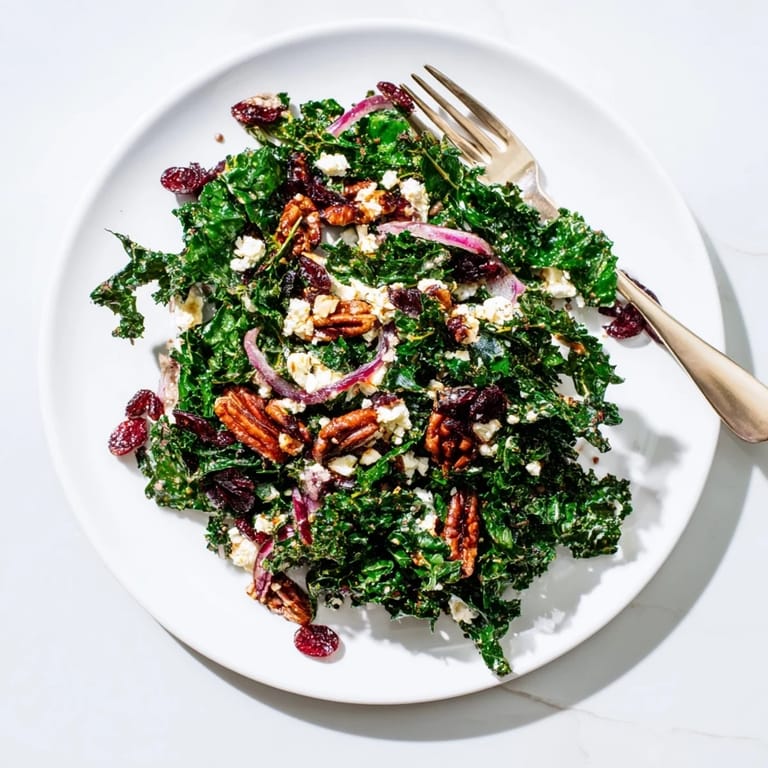 Hearty warm kale salad tossed in sweet-and-tangy maple mustard dressing, topped with crunchy nuts and cranberries.