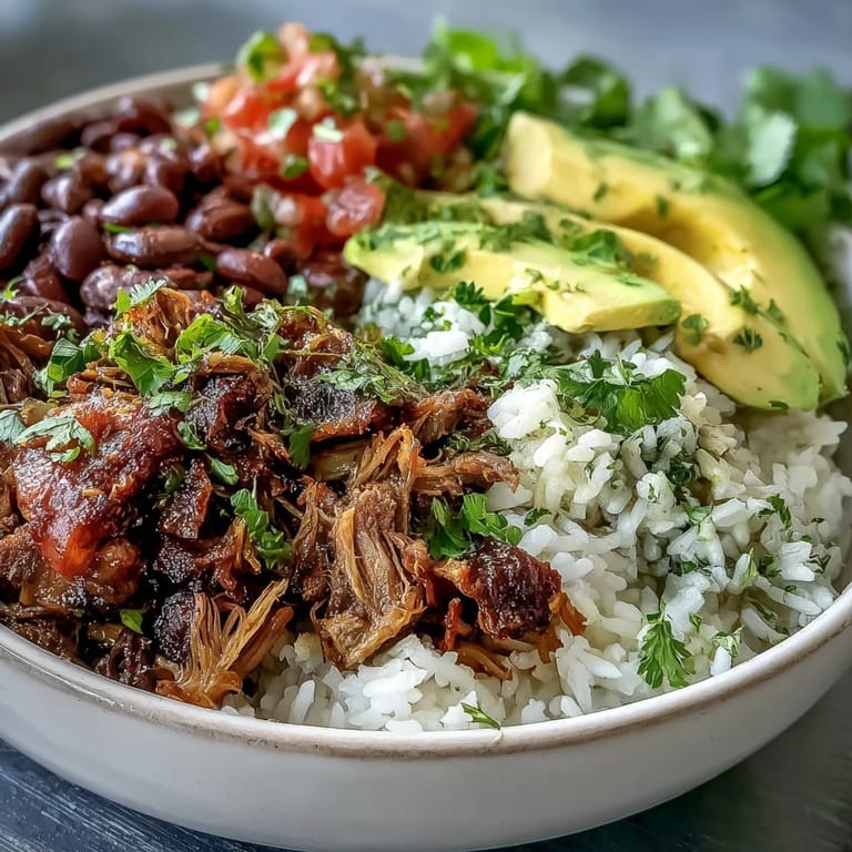 Carnitas Bowl: tender shredded pork and creamy avocado over a bed of seasoned rice and beans.