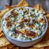 Creamy elote dip with charred corn, cotija cheese, and lime, served with crispy tortilla chips for a perfect Cinco de Mayo appetizer.