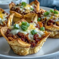 Crispy wonton mini taco cups bursting with savory filling and melted cheese, perfect appetizer.